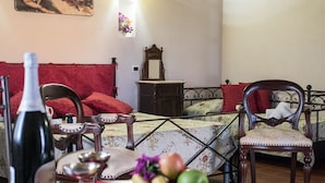 Une chambre à coucher avec un lit, une chaise, une table sur laquelle se trouvent une bouteille, un verre et des fruits.