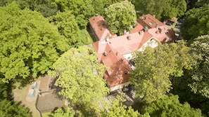 An aerial view of a residential area with a house featuring a red roof, surrounded by lush green trees. - Park Hotel (Szczecin)