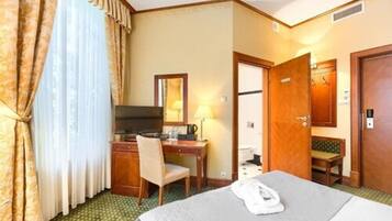 Ein Hotelzimmer mit Bett, Schreibtisch, Stuhl, Fernseher und Badezimmertür.