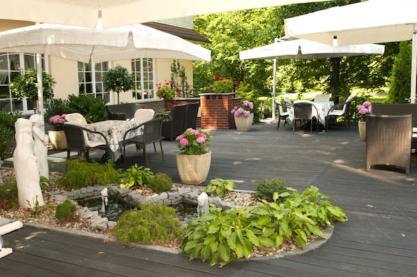 An outdoor patio with seating, umbrellas, and a small water feature.