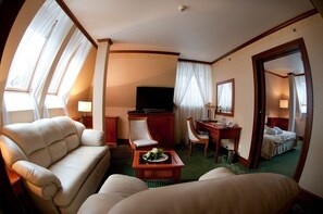 Ein Hotelzimmer mit einer Couch, einem Schreibtisch, einem Fernseher und einem Bett.