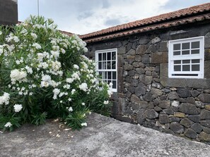 A stone building with a tiled roof and two white-framed windows. - Casa das Barcas (Sao Roque do Pico)