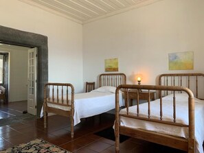 A bedroom with two wooden beds, a small table, and a chair. - Casa das Barcas (Sao Roque do Pico)