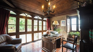 A room with a wooden ceiling, a desk with a lamp, a leather chair, and large windows with curtains. - Quinta da Mata (Chaves)