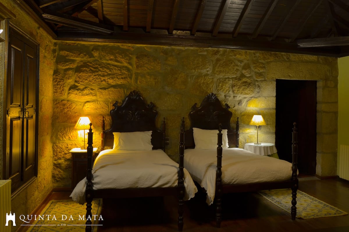 Una habitación con dos camas de madera, paredes de piedra y techo de madera.