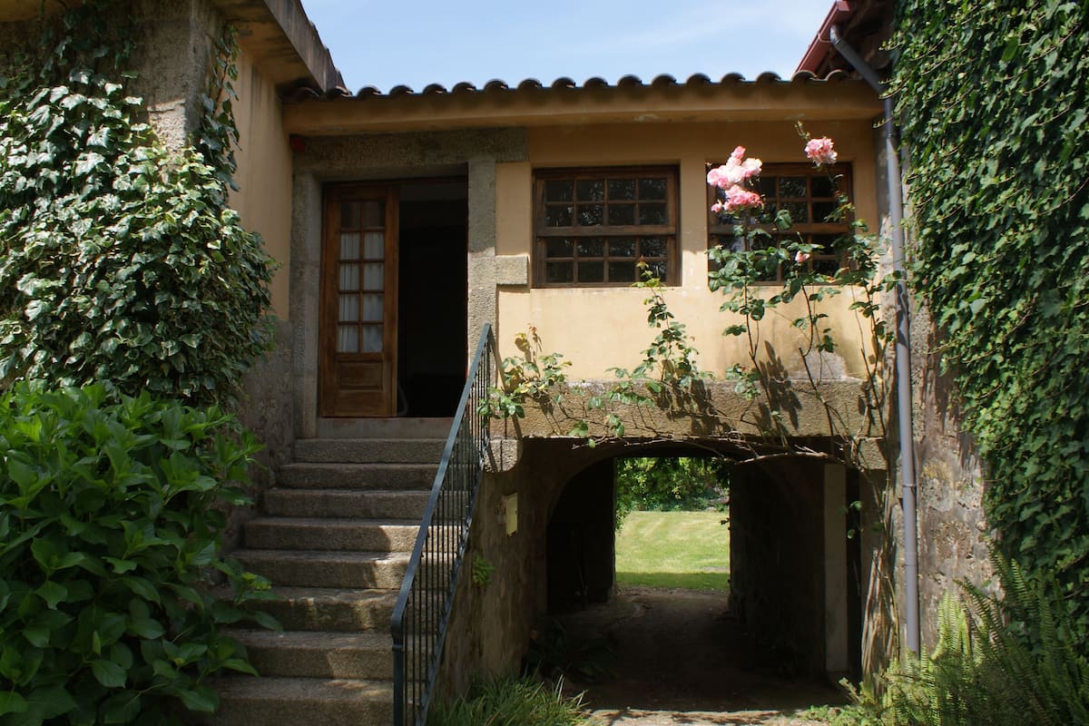 A stone staircase leading to a house with a wooden door and windows.