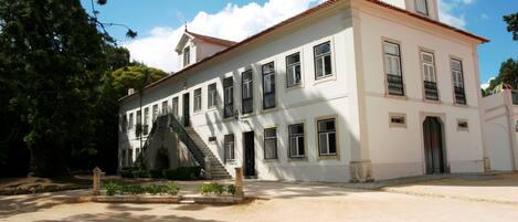 A large, white building with multiple windows and a central staircase.