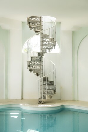 Una escalera de caracol con barandillas de metal decorativas junto a una piscina.