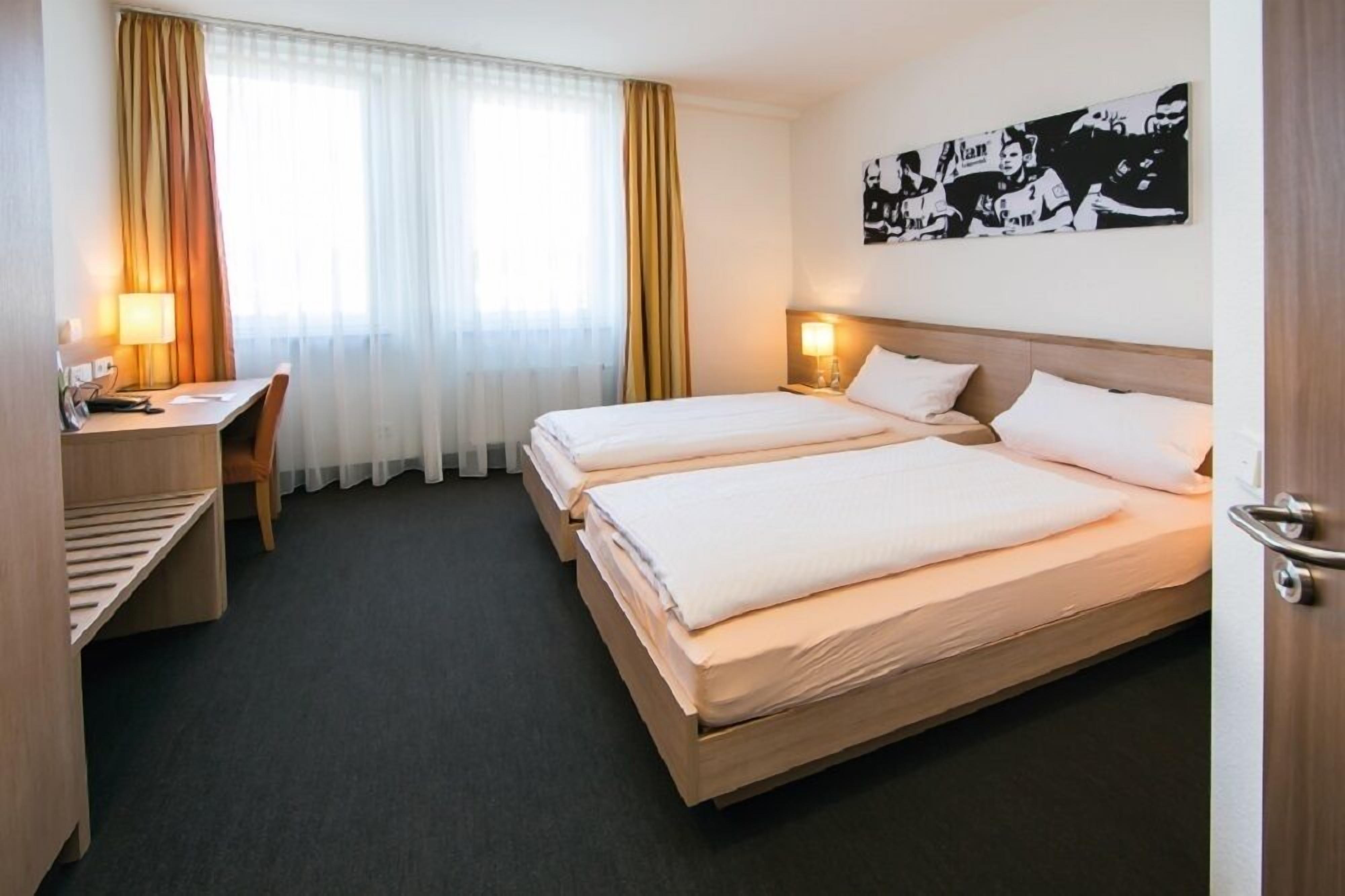 Una habitación de hotel con dos camas, un escritorio y una silla.