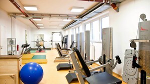 A gym with exercise equipment, a blue exercise ball, and a mirror on the wall.