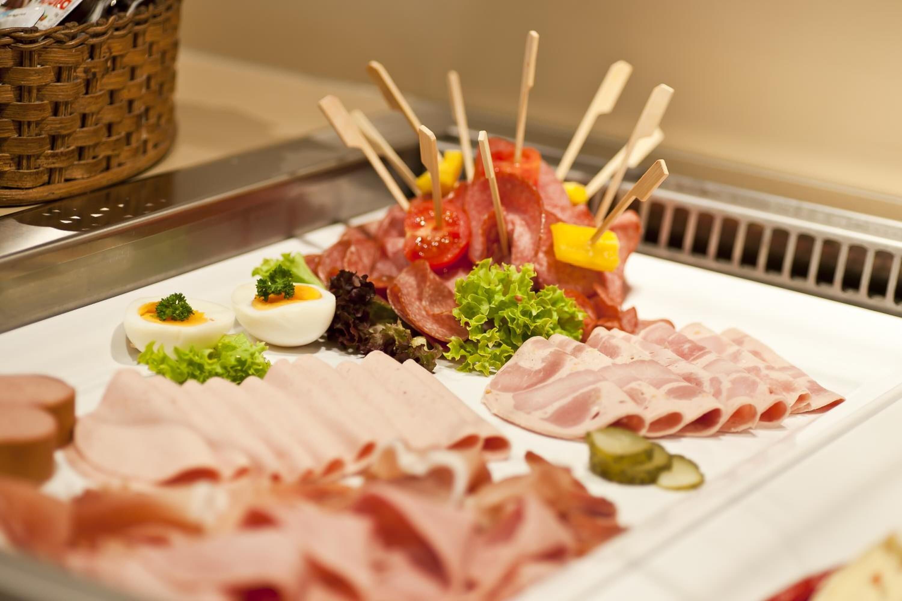 Una tabla de embutidos con diversos tipos de carne, verduras y huevos.