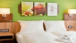 A hotel room with a bed, two bedside tables, and wall-mounted lamps.