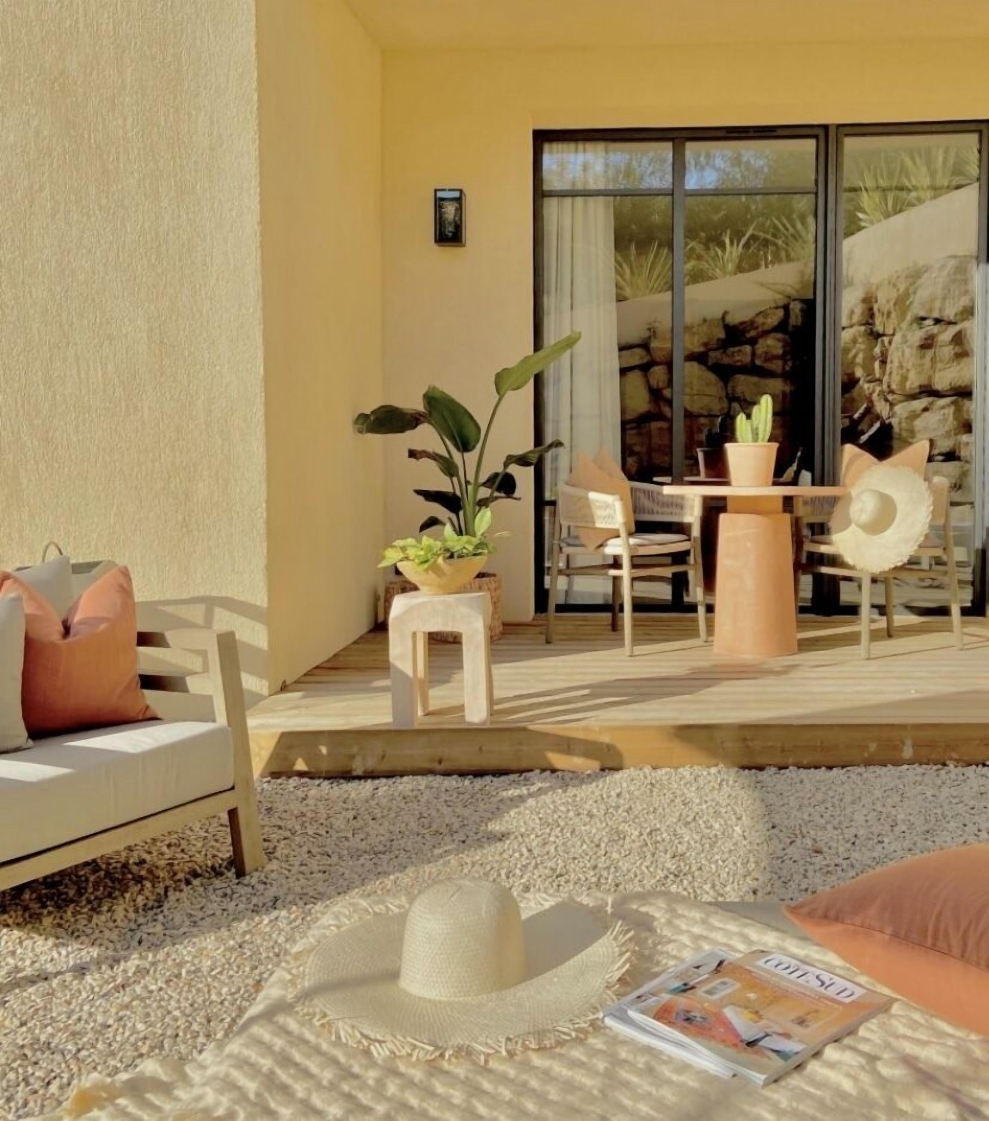 Une terrasse avec un canapé blanc, une table à manger, des chaises et une plante en pot.