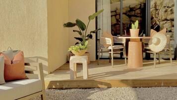Une terrasse avec un canapé blanc, une table à manger, des chaises et une plante en pot.