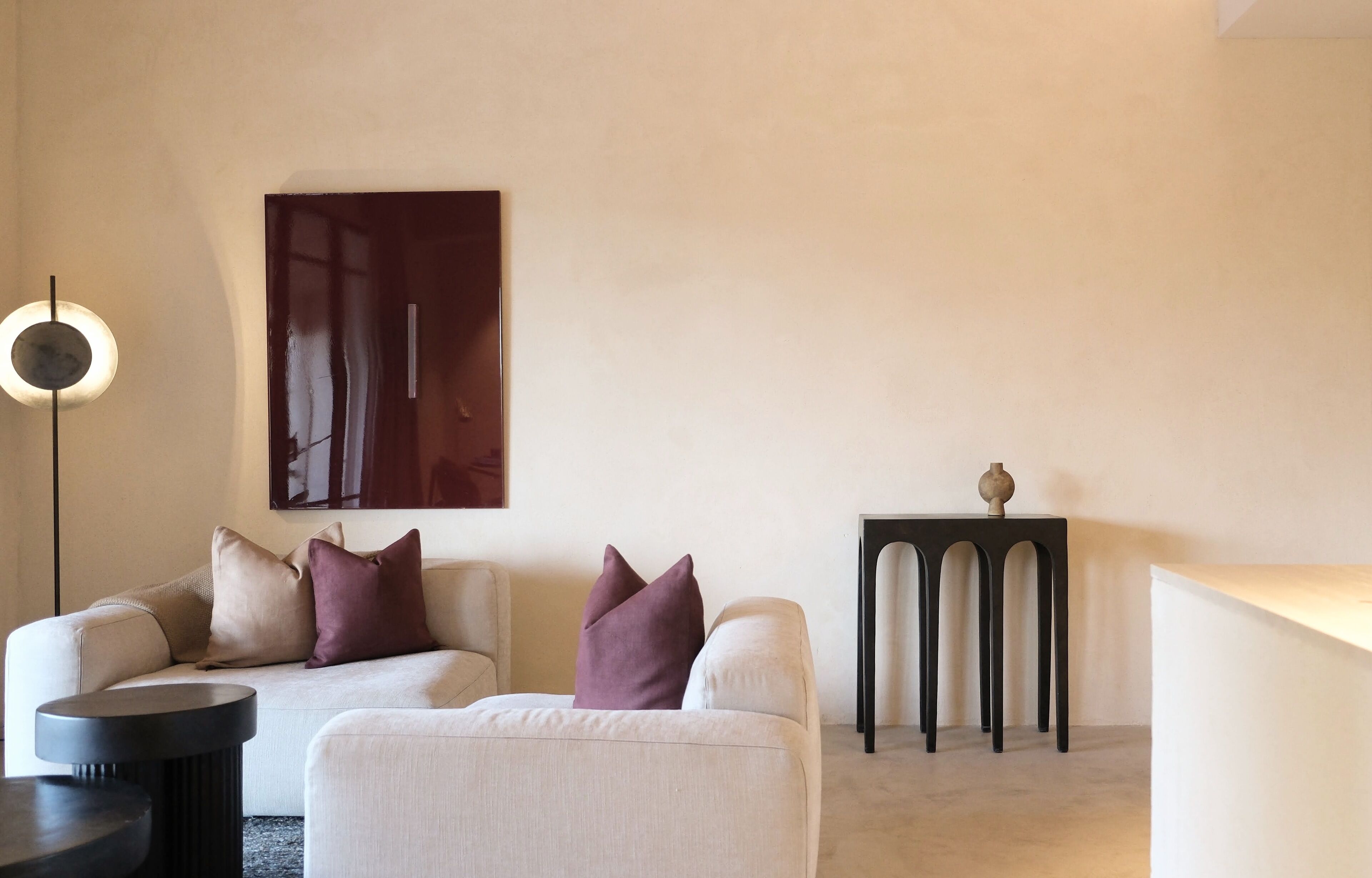 Een moderne woonkamer met een bank, een klein tafeltje en een decoratief object op een voetstuk.