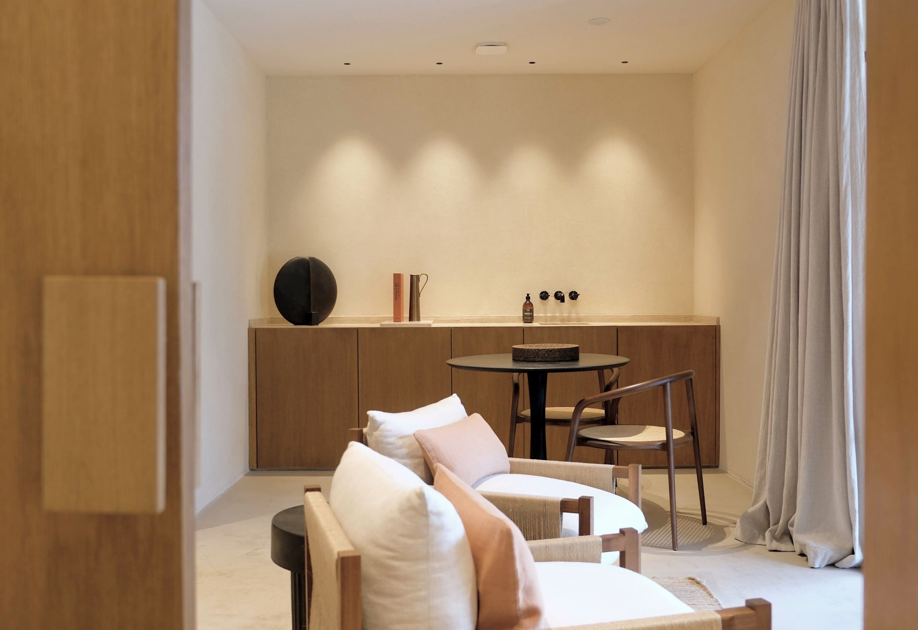 A modern, compact living space with a sofa set, a small round table, and a kitchen area with cabinets and a countertop.
