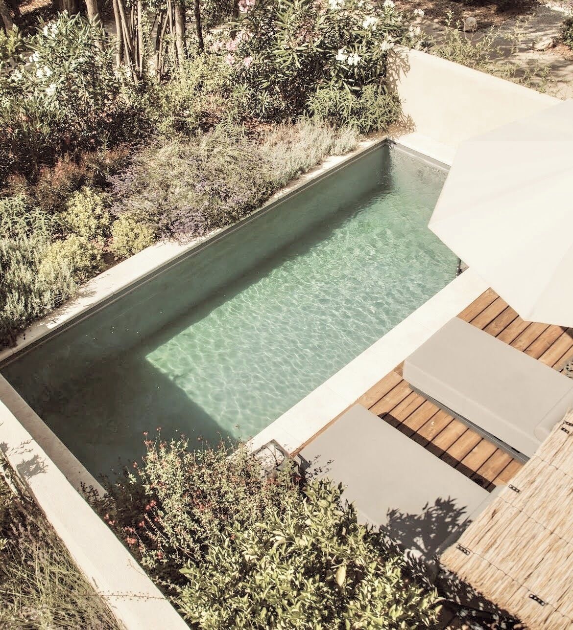 A rectangular swimming pool with clear water, surrounded by a concrete deck and wooden decking.
