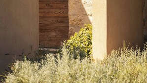 An arched doorway with a wooden panel, a stone wall, and a small wall-mounted light fixture. - Toile Blanche (Saint-Paul-de-Vence)