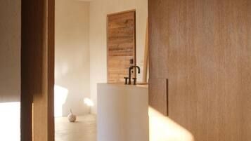 A modern bathroom with a wooden vanity, a black faucet, and a wooden door in the background.