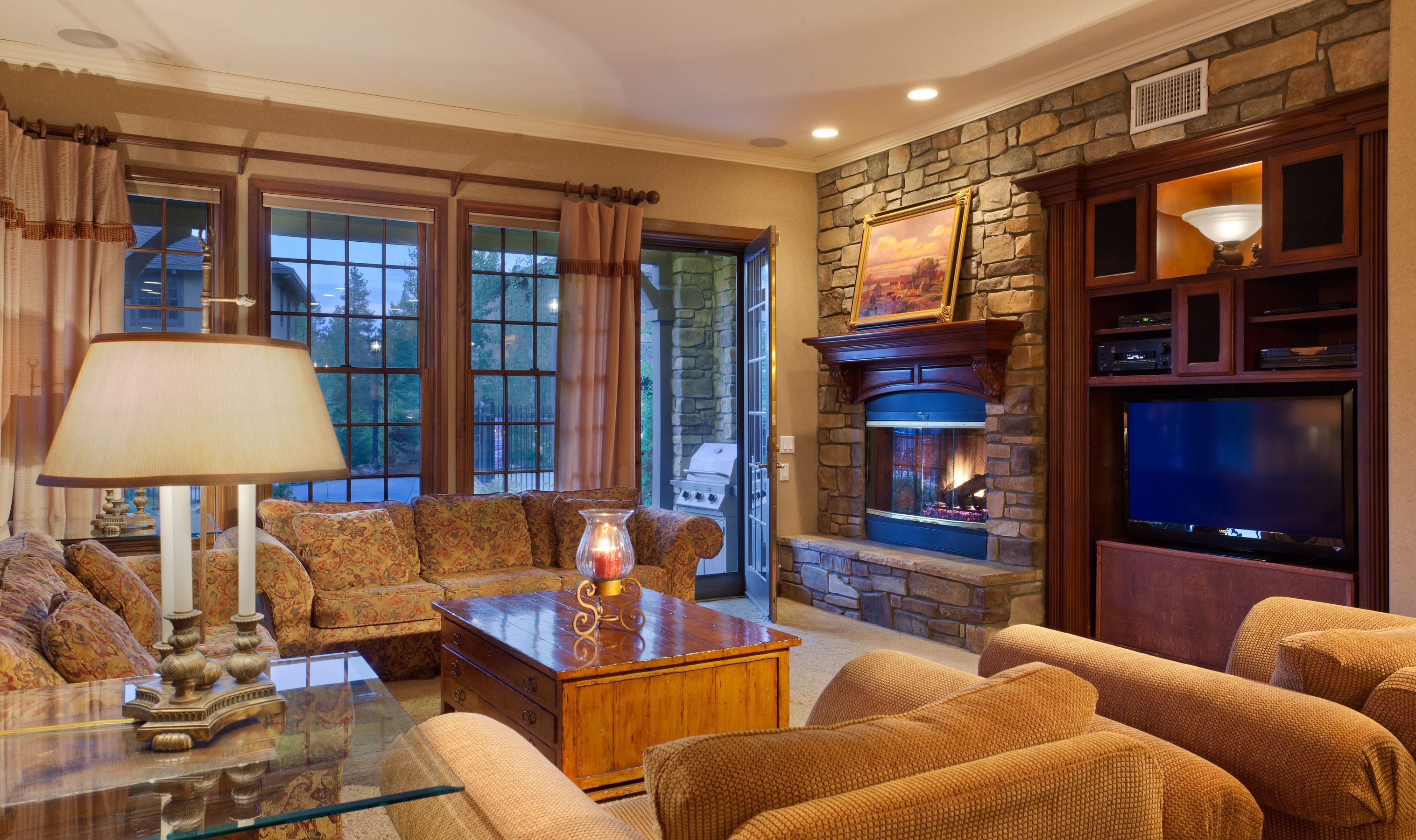 A cozy living room with a stone fireplace, comfortable seating, and a television.