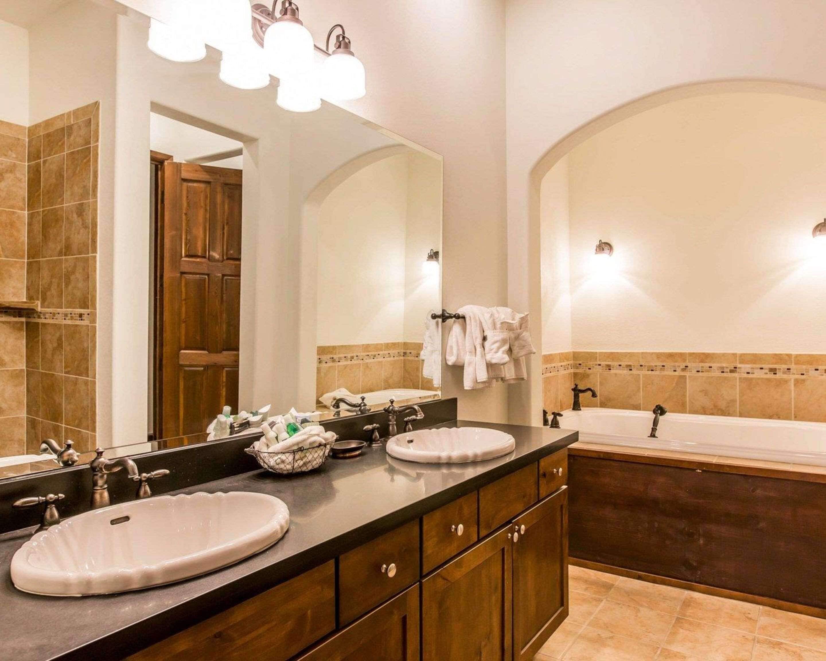 A bathroom with two sinks, a bathtub, and a large mirror.