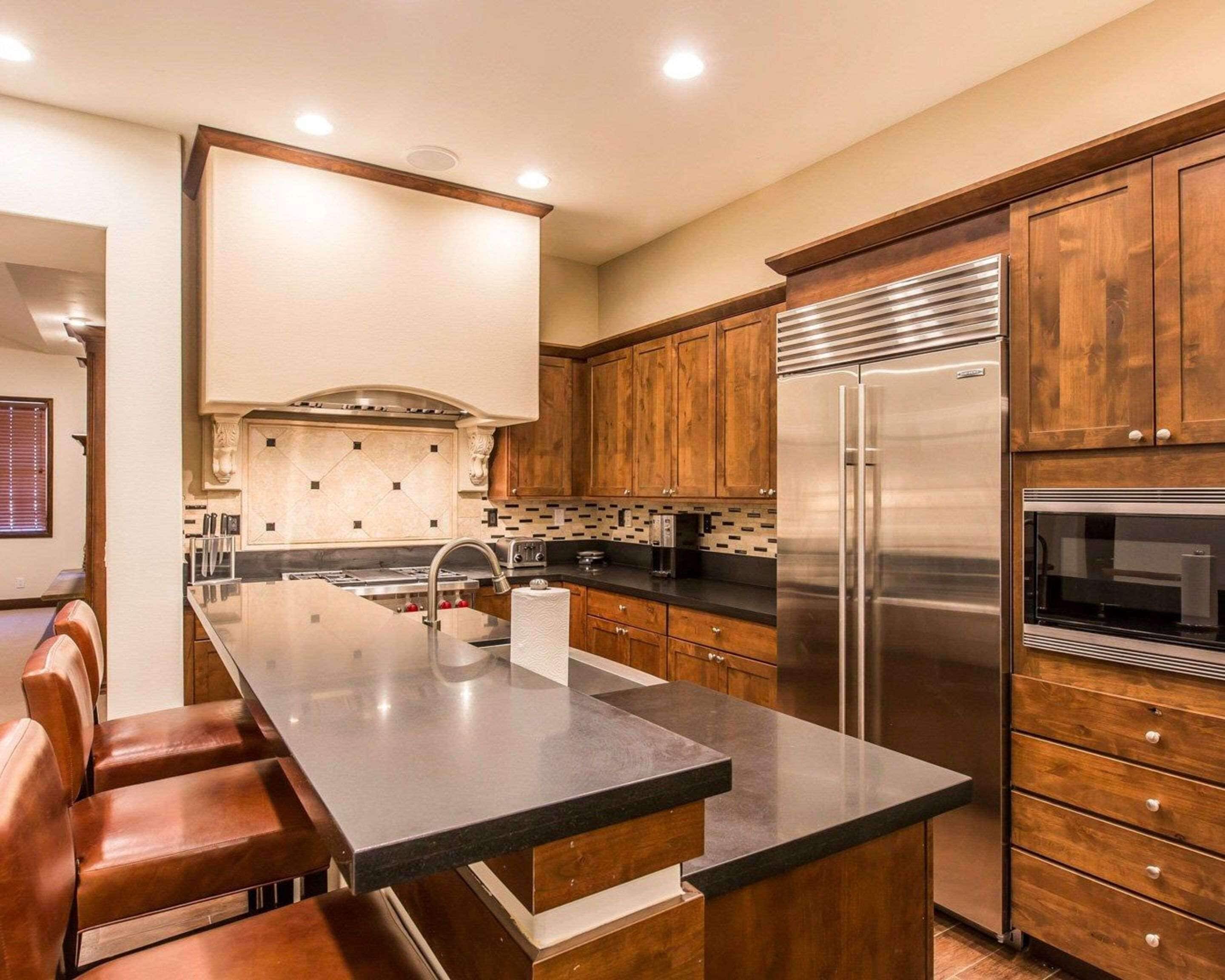 Una cocina moderna con una isla central, armarios de madera y electrodomésticos de acero inoxidable, incluyendo un horno empotrado.
