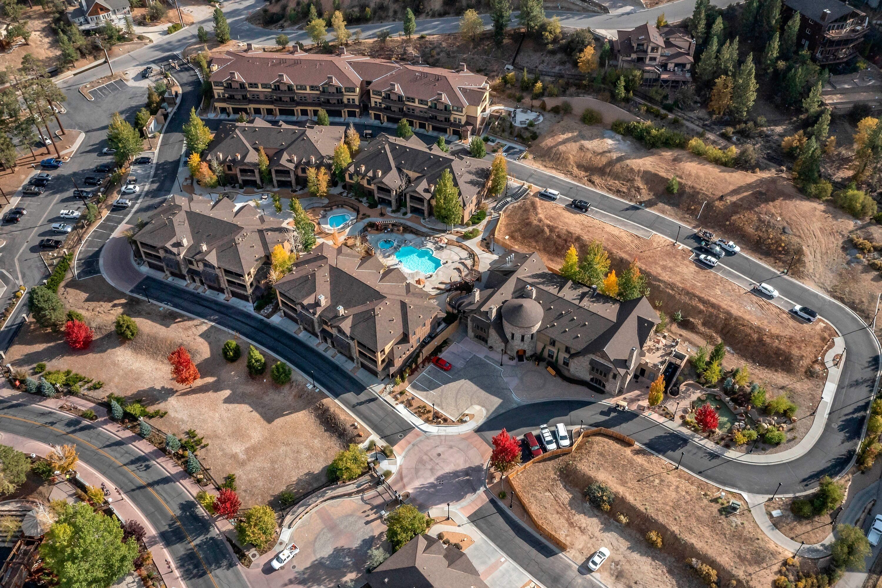 Vista aérea de un complejo turístico con varias construcciones, piscina y aparcamiento.