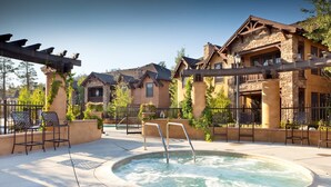 Un espace piscine avec des chaises et un jacuzzi, entouré de bâtiments en pierre dotés de balcons.