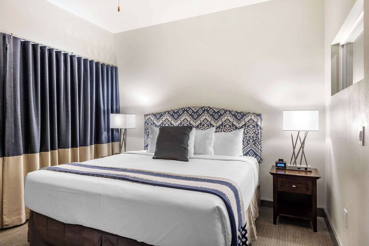 Ein Hotelzimmer mit einem großen Bett, einem Nachttisch mit Lampe und einem gemusterten Kopfteil.