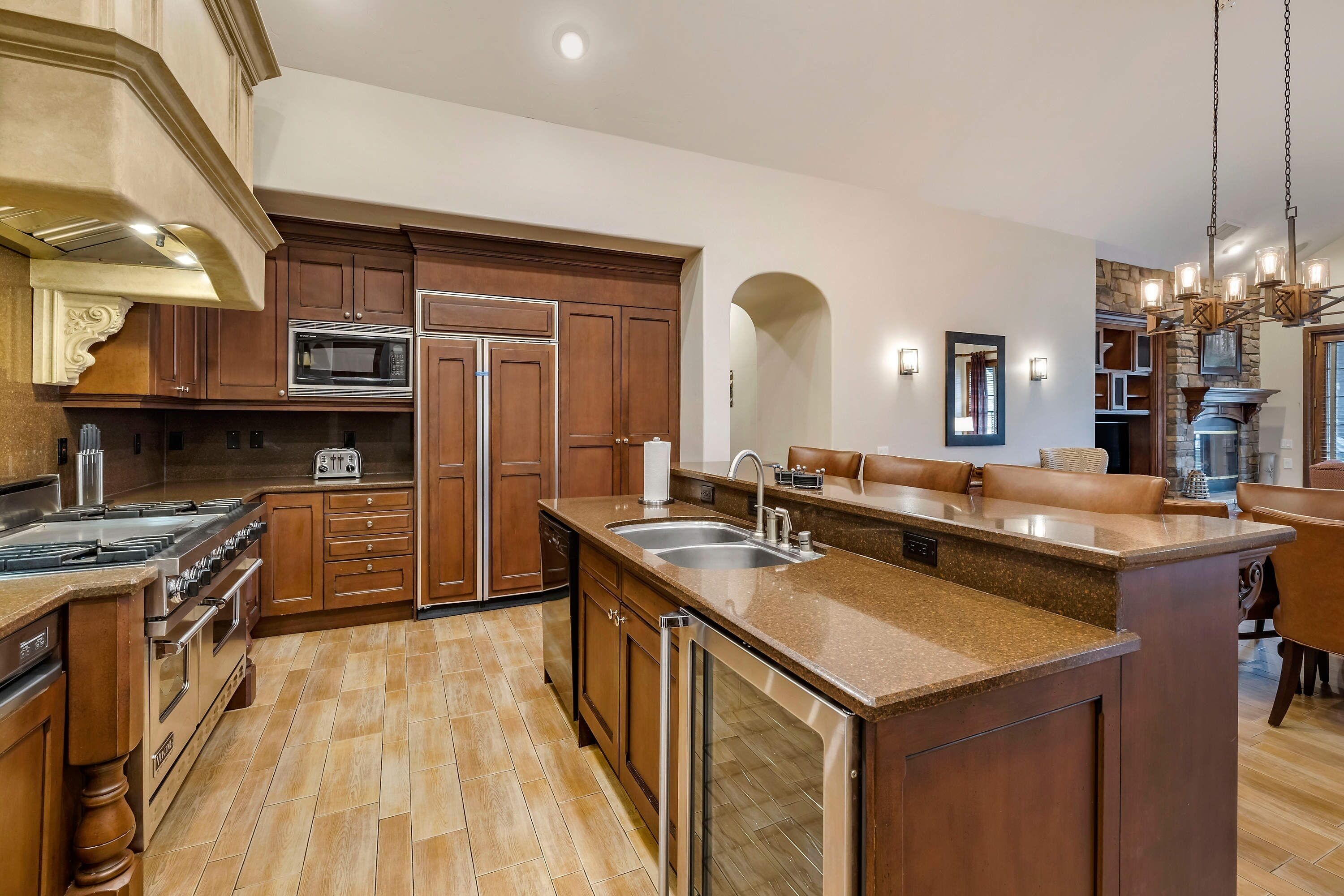 A spacious kitchen with wooden cabinets, a central island, stainless steel appliances, and a dining area with leather seating.