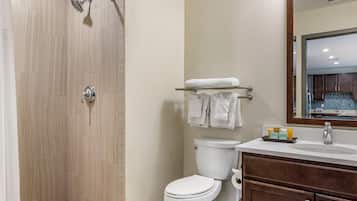 A bathroom with a shower, toilet, sink, and a towel rack.