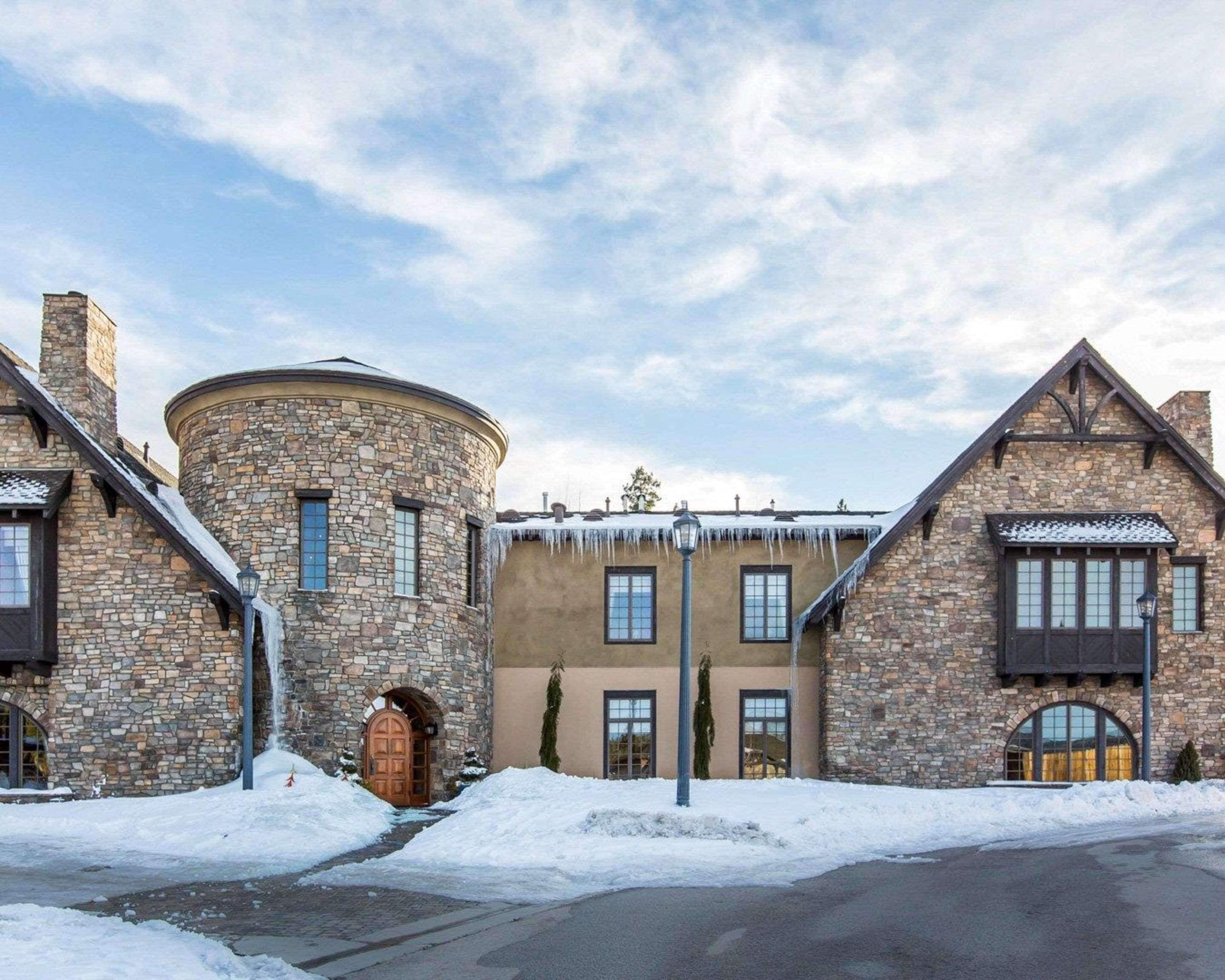 A stone building with a round tower, multiple windows, and a snow-covered landscape.