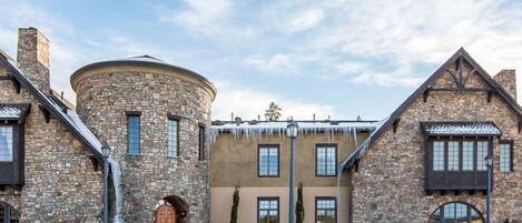 Un edificio de piedra con una torre redonda, varias ventanas y un paisaje cubierto de nieve.