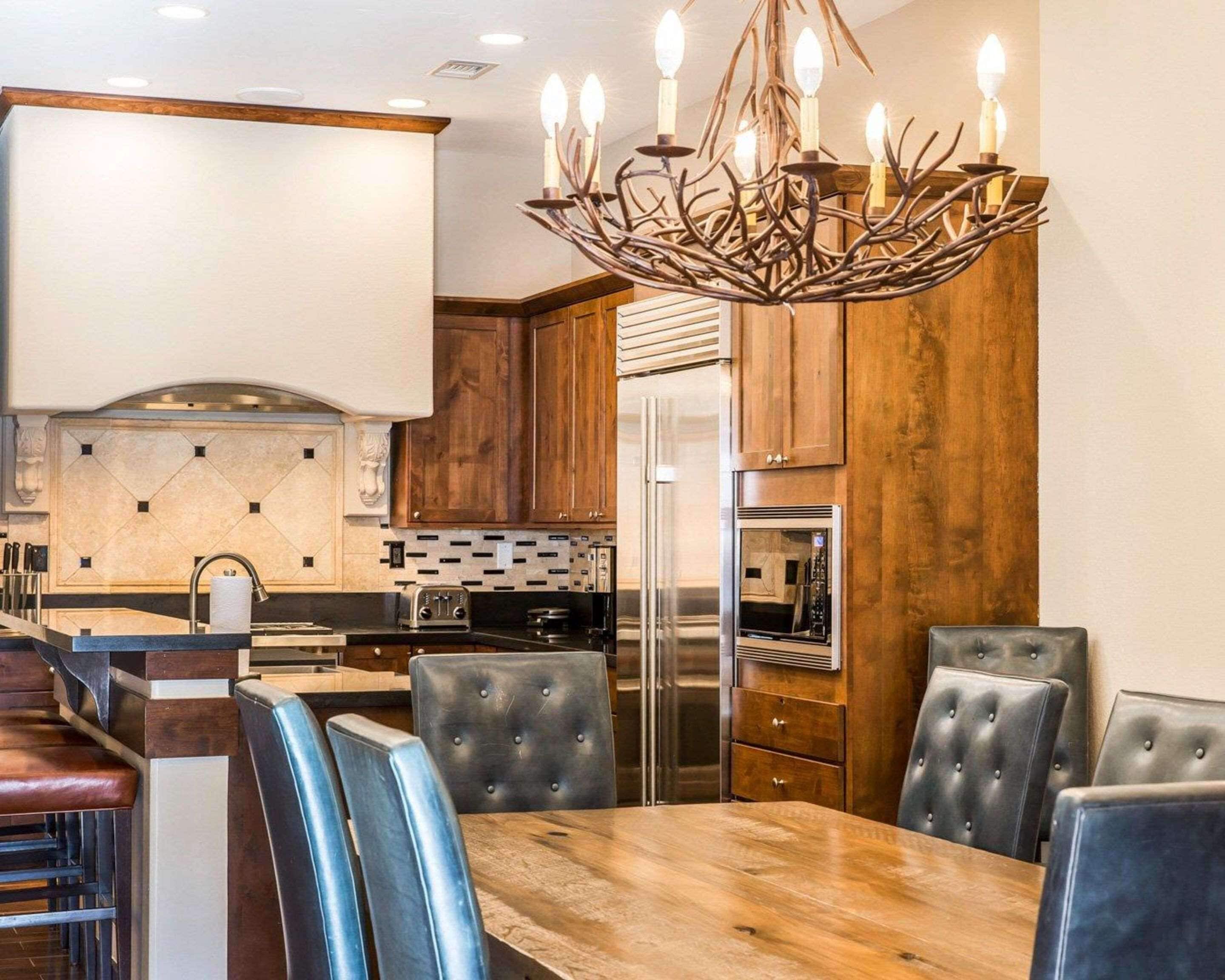 A modern kitchen with a central island, dark wood cabinets, and a chandelier.