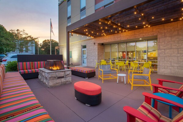 An outdoor seating area with a fire pit, colorful striped sofas, and yellow chairs.