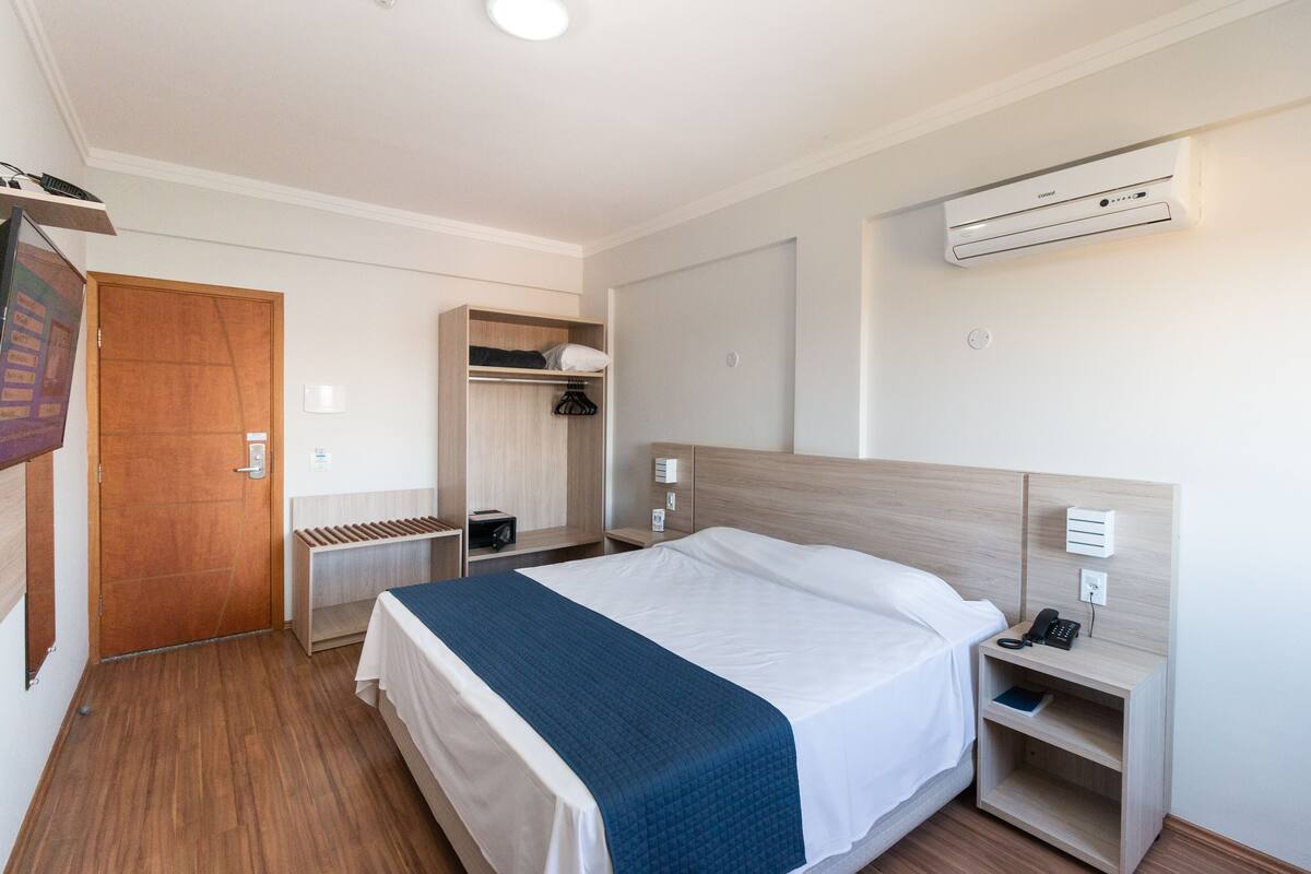 Een hotelkamer met een bed, nachtkastje en een inbouwkast.
