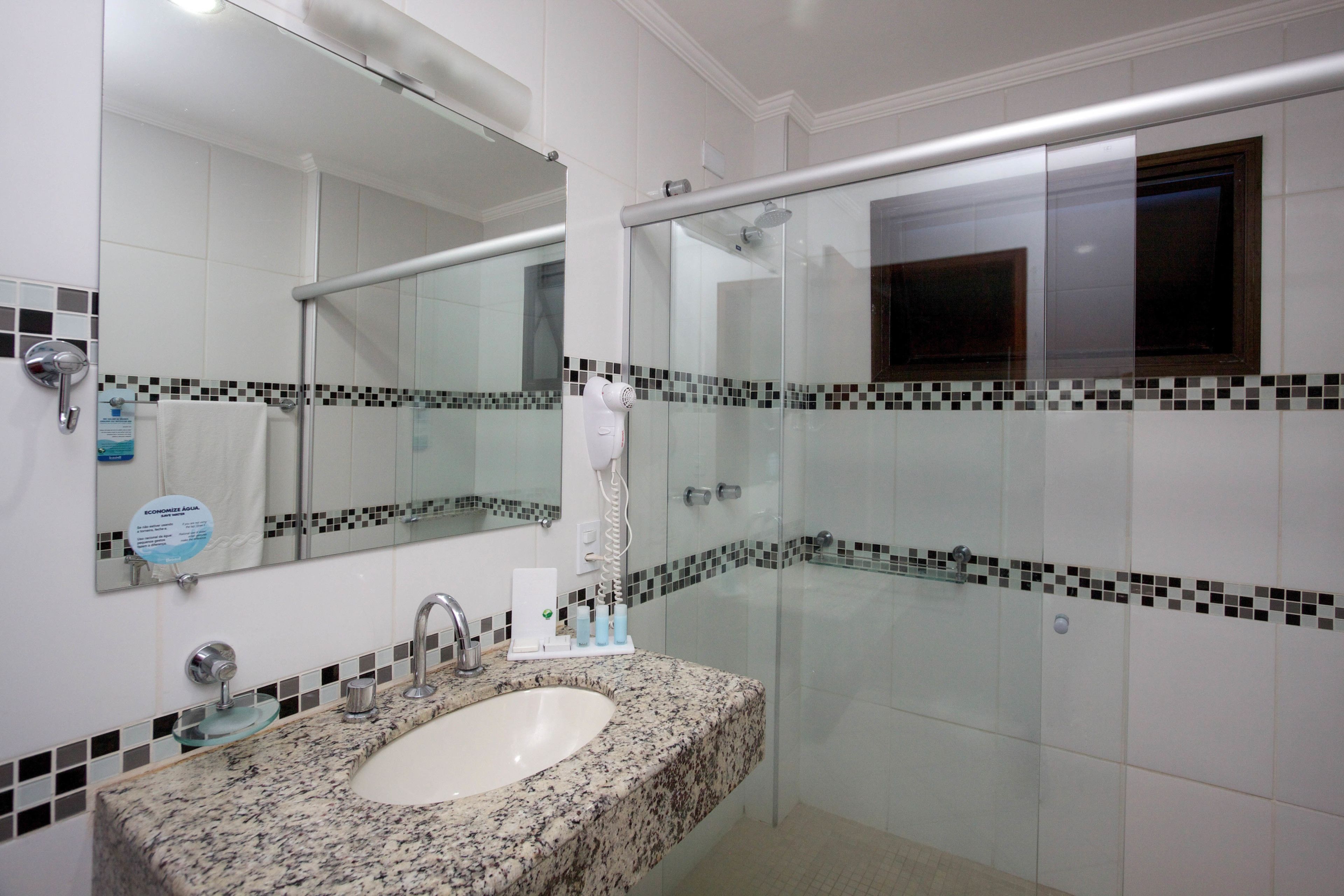 A bathroom with a granite sink, a glass shower enclosure, and a tiled floor.