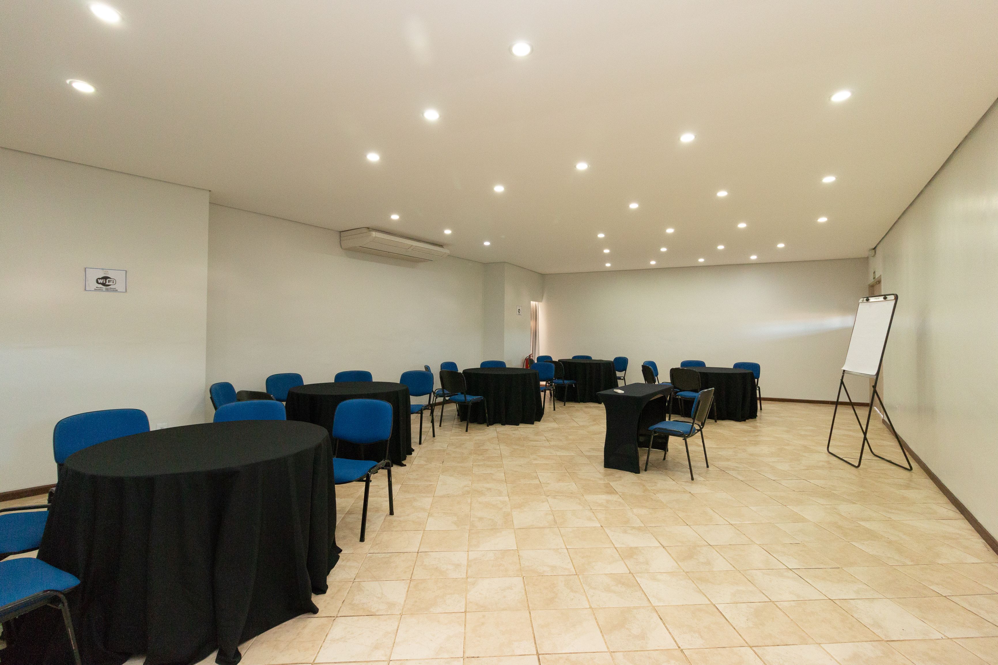 A conference room with round tables, blue chairs, and a whiteboard.