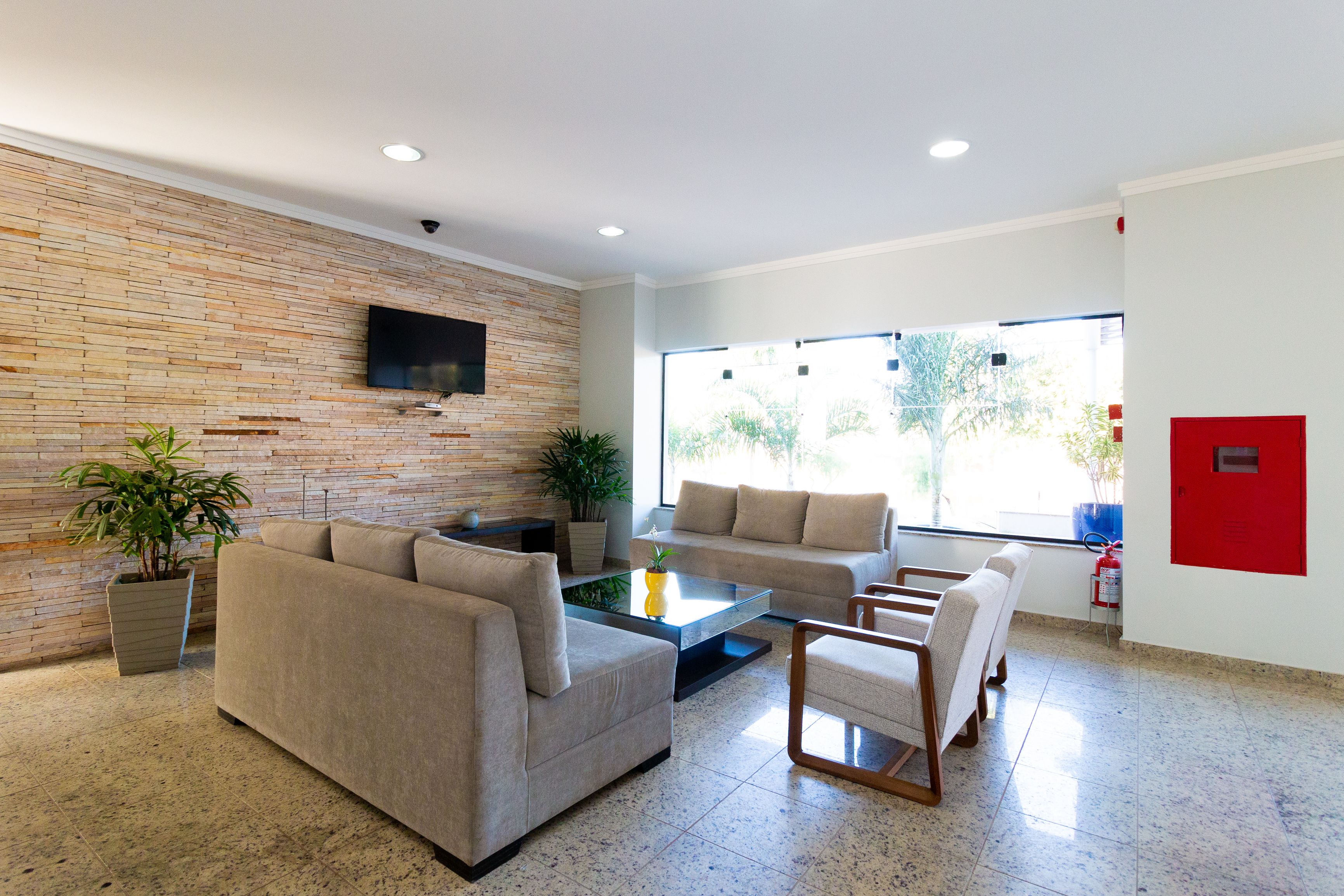 A modern living room with a stone wall, a flat-screen TV, two sofas, a coffee table, and a fire extinguisher.