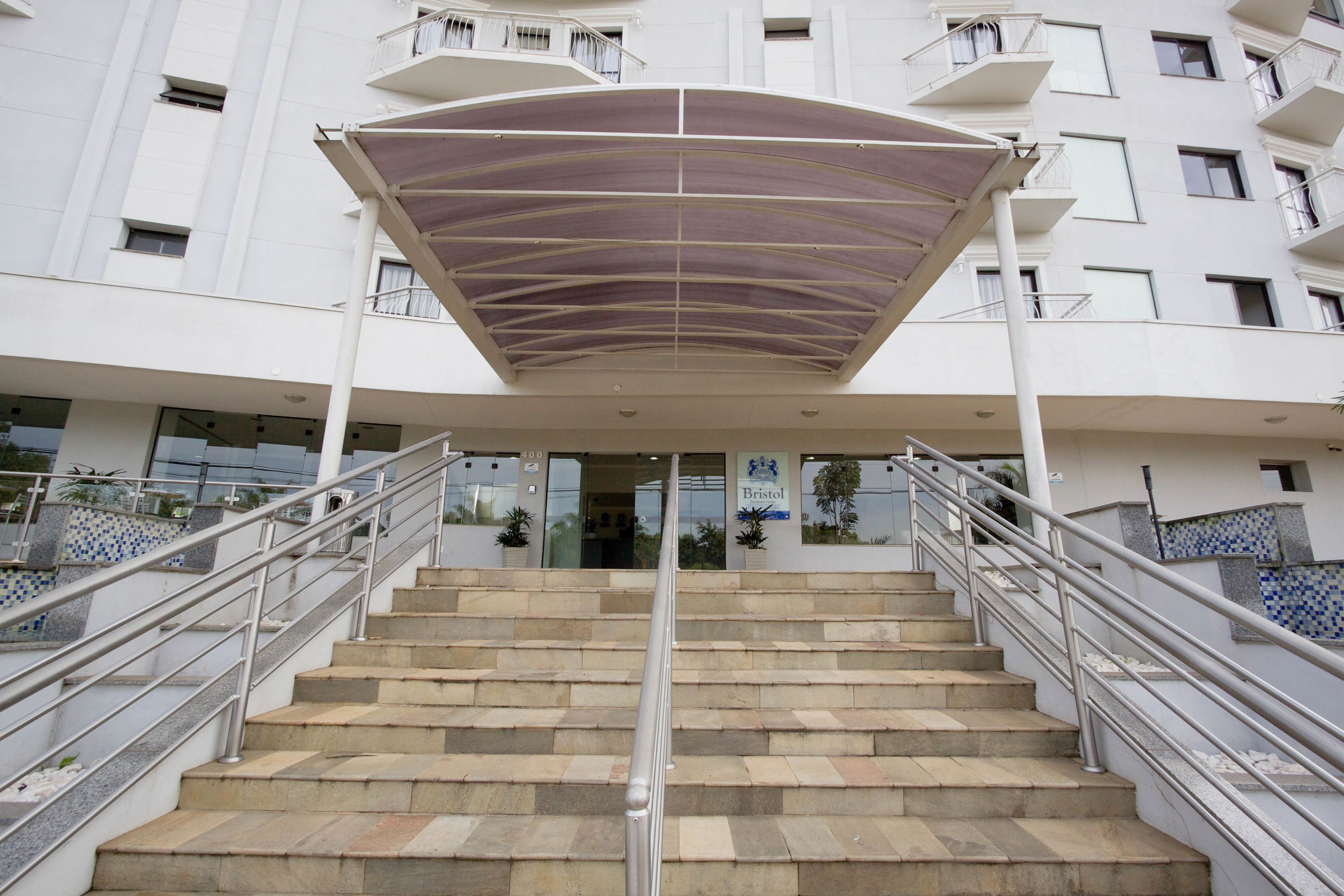 Un escalier menant à l’entrée d’un bâtiment, avec une zone couverte au-dessus.
