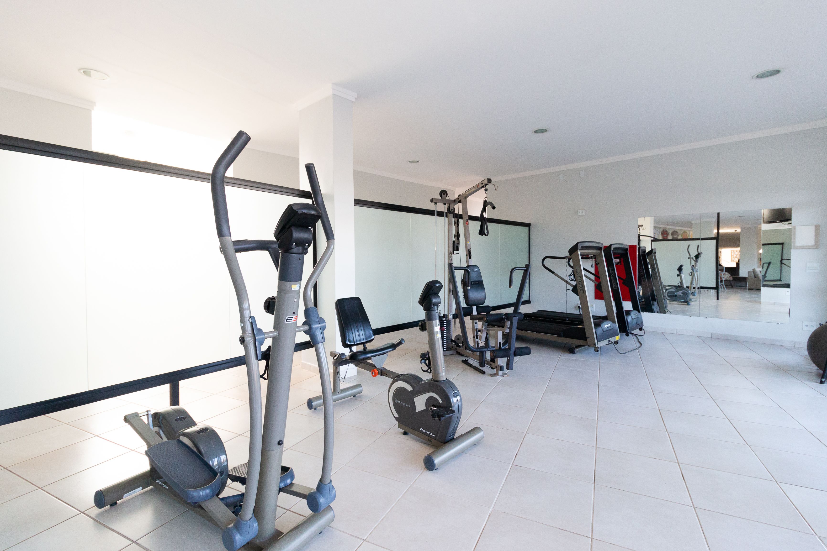 A modern gym with various exercise equipment, including treadmills, a bench press, and weight machines.
