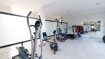 A modern gym with various exercise equipment, including treadmills, a bench press, and weight machines.
