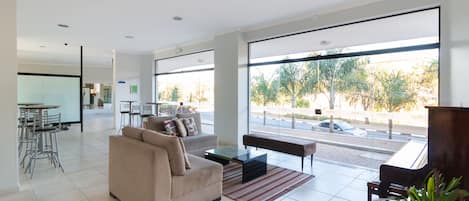 A spacious living area with a sofa, coffee table, and a view of the street through large windows.
