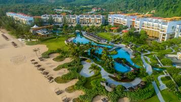 A resort with multiple buildings, a large swimming pool, and a beach area.