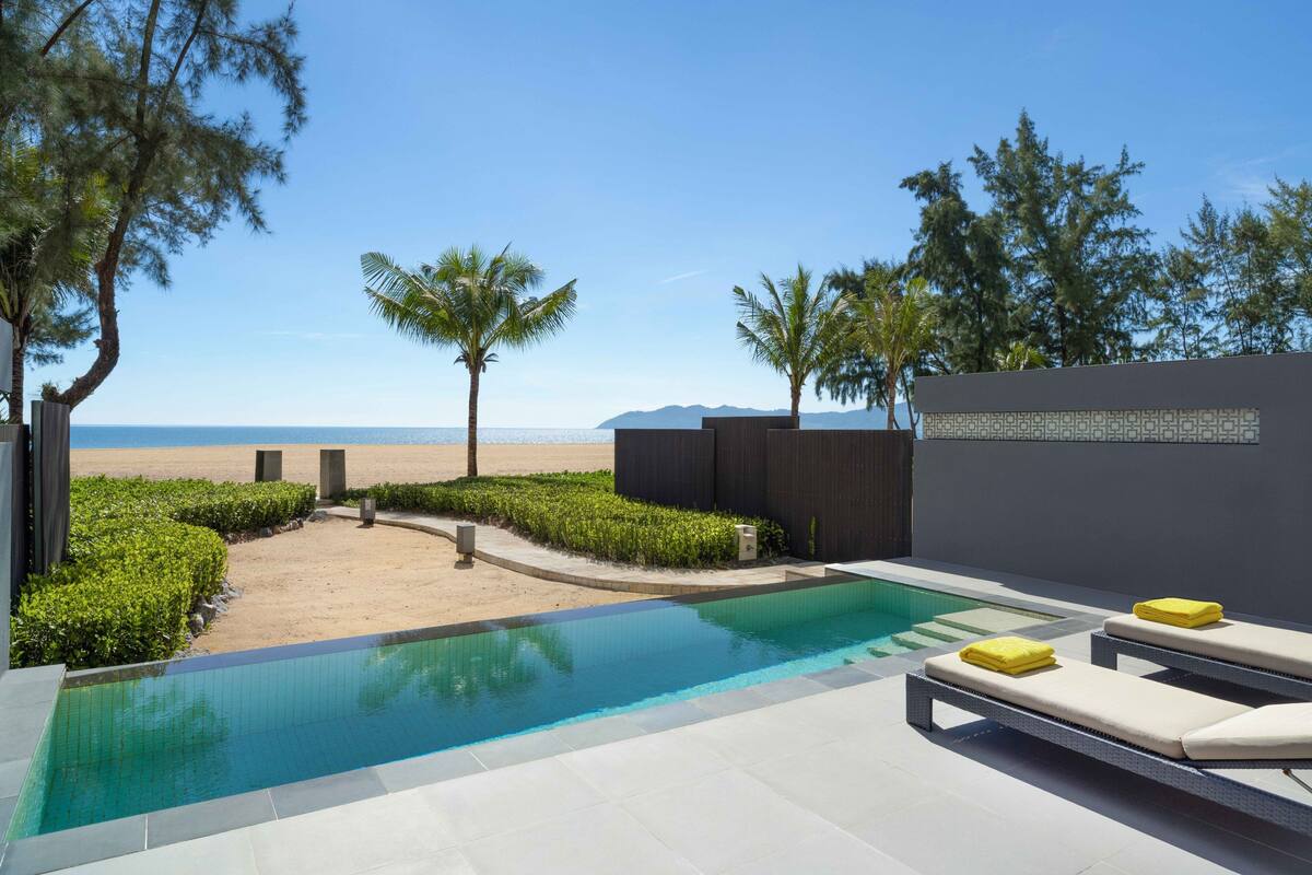 A pool area with lounge chairs and a view of the beach.