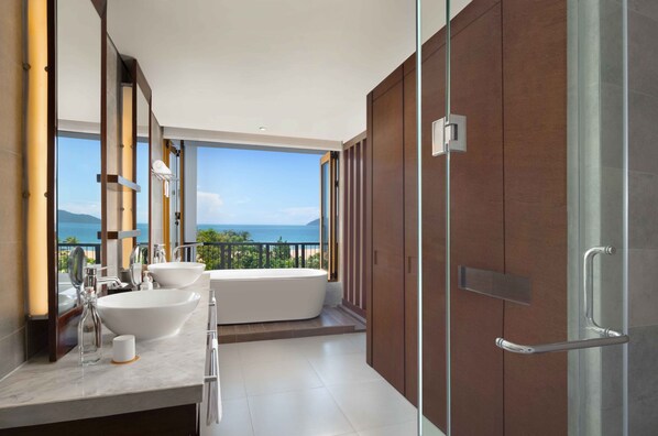 A modern bathroom with a large bathtub, two sinks, and a glass shower door. - Angsana Lang Co (Hue)