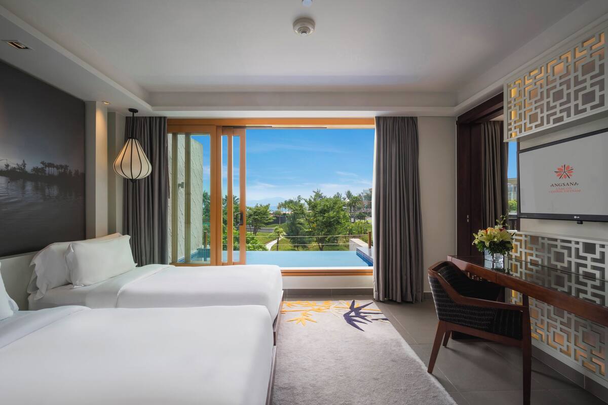 A hotel room with two beds, a desk, a chair, a view of a swimming pool, and a decorative wall panel.