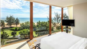 A hotel room with a large window offering a view of the beach and ocean. - Angsana Lang Co (Hue)