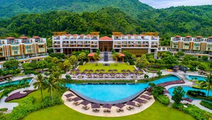 A resort with multiple buildings, a central pool, and lush greenery. - Angsana Lang Co (Hue)