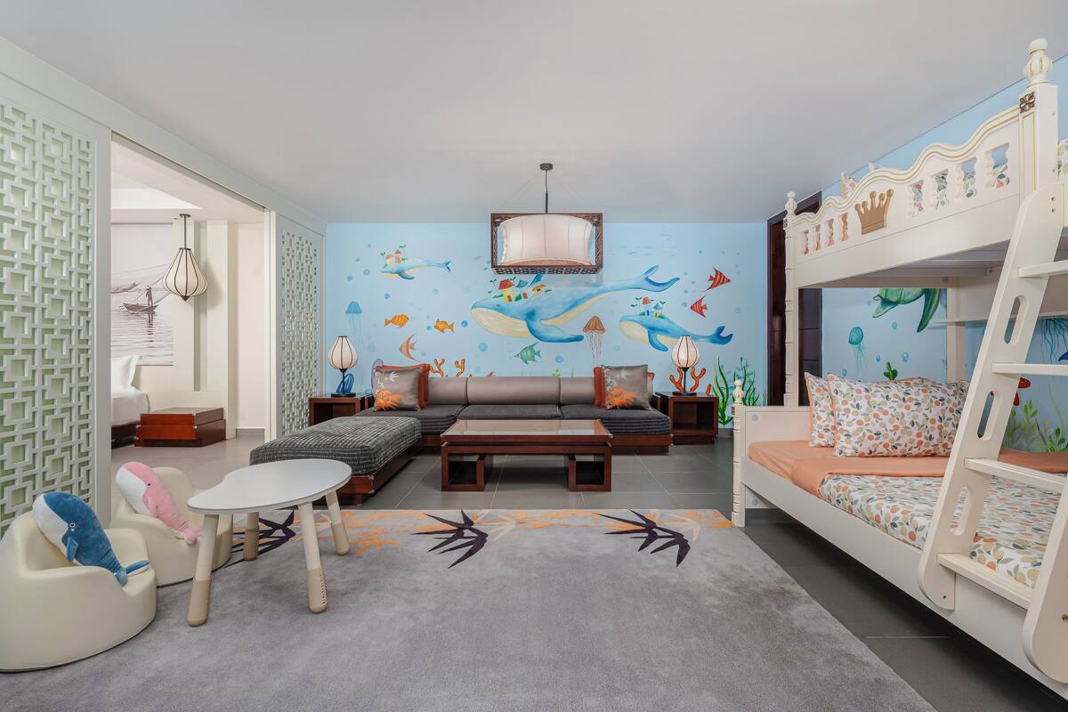 A children's room with a bunk bed, sofa, and a mural of sea creatures.
